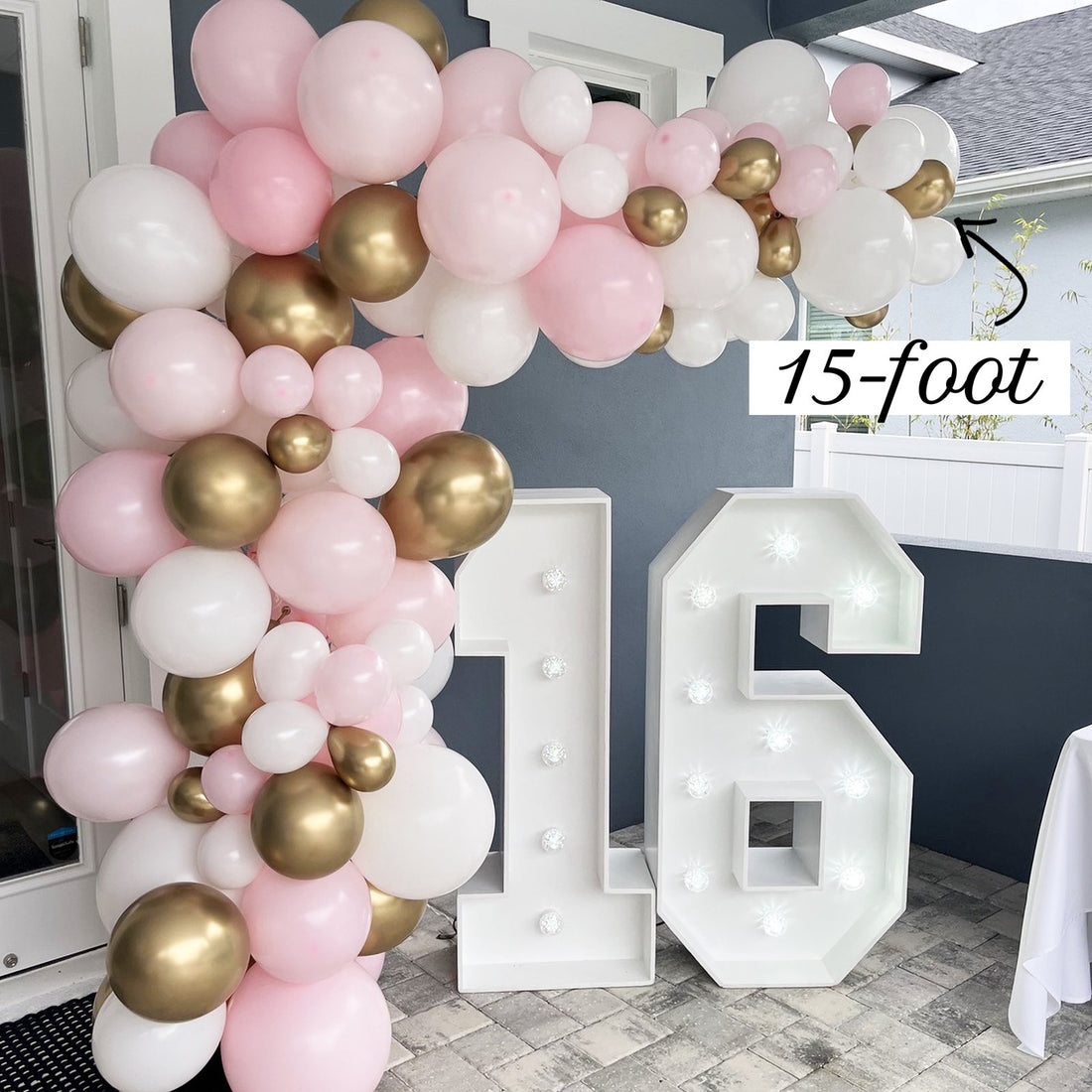 15ft pink, white and gold balloon garland framing a doorway with marquee number 16, labeled 15-foot